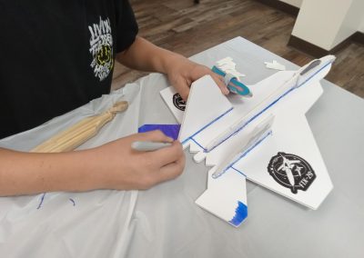 Person crafting a white model jet with blue outlines and black stickers.
