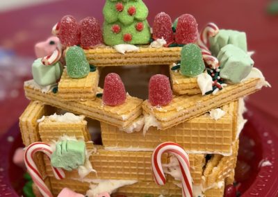 Edible house made from wafers with candy decorations on a red plate.