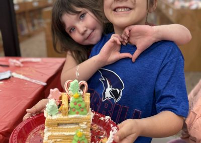 Two children smile, holding a decorated dessert plate in a library setting.