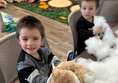 Children are participating in a stuffed animal activity in a room with a colorful rug.