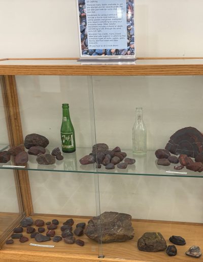 Display of various labeled stones and minerals in a glass cabinet.