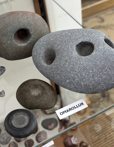 Smooth stones with indentations on a glass display, labeled "OMAROLLUK."